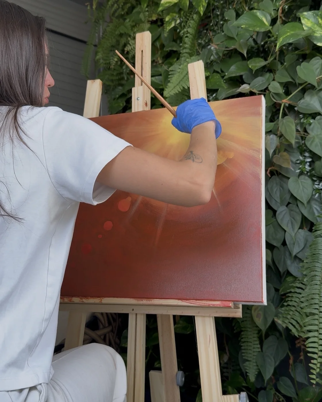 Nicole pintando uma tela laranja