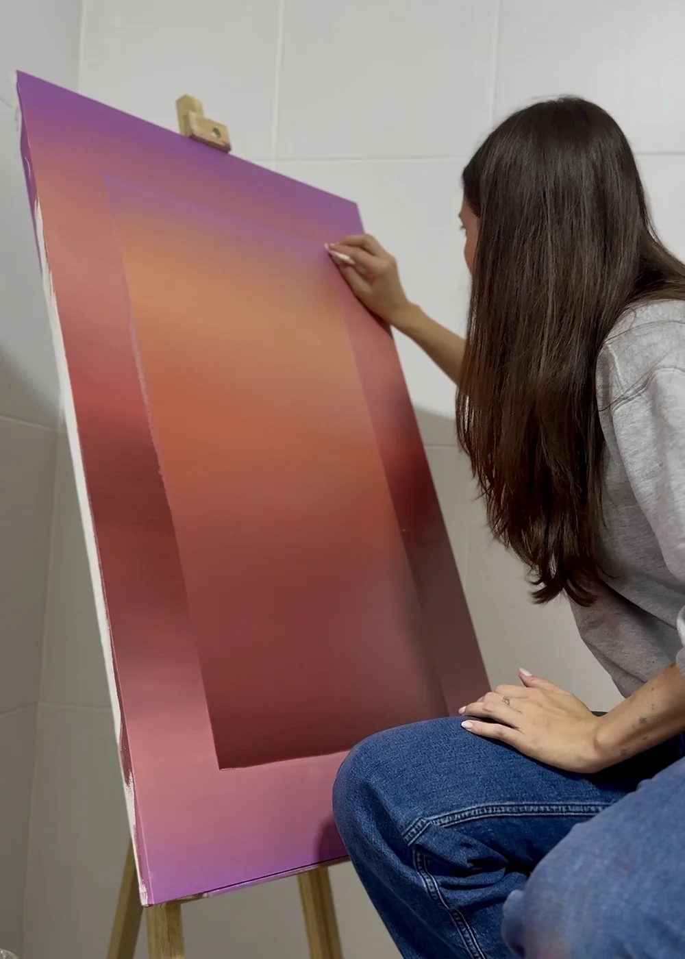 Nicole pintando uma tela em degradê rosa e laranja