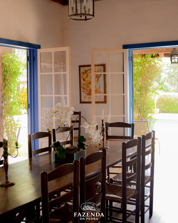 Sala de jantar com mesa de madeira e portas azuis abertas para o jardim