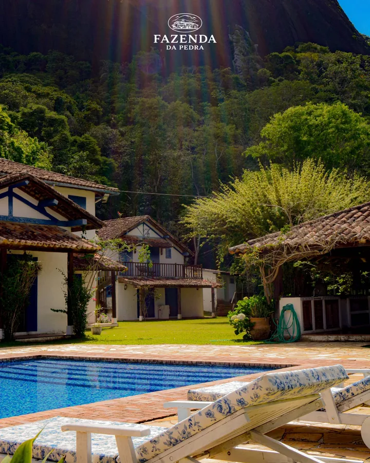 Luz do sol sobre as casas e a piscina, com espreguiçadeiras floridas