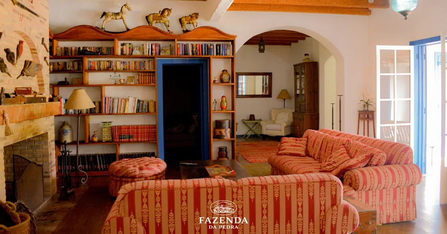 Sala de estar com lareira, estante de livros e sofás listrados