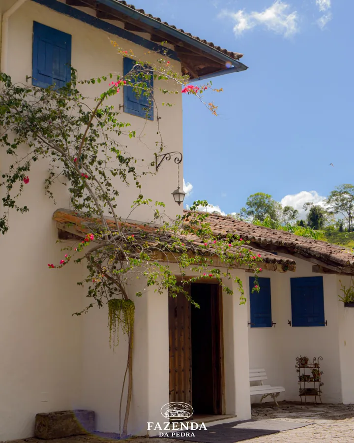 Fachada branca com buganvília, lampião e janelas azuis