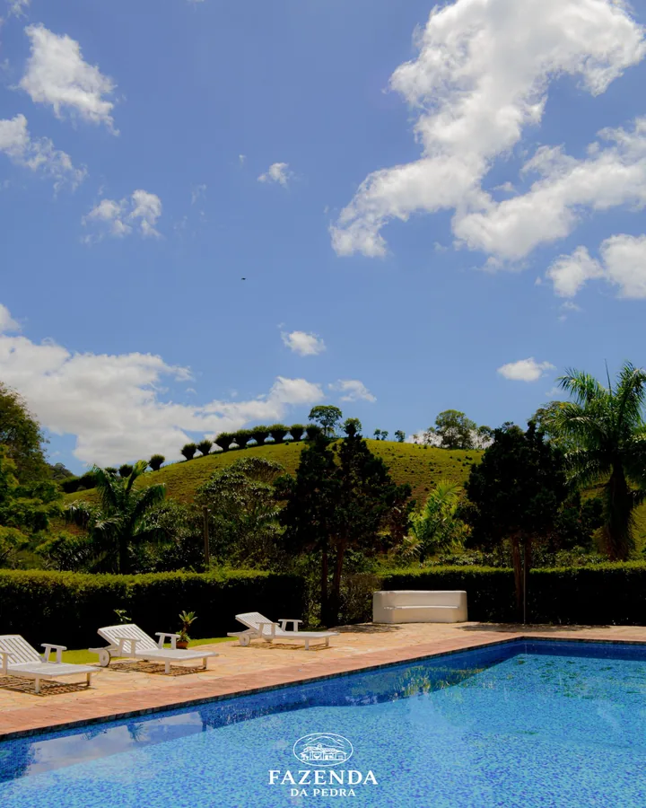 Piscina, espreguiçadeiras e o morro verde sob o céu azul