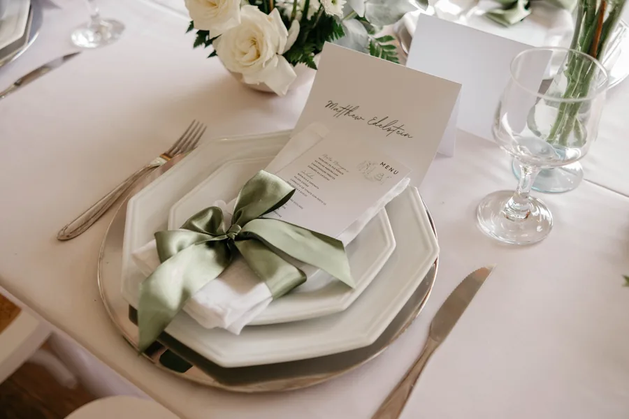 Lugar à mesa com menu, laço verde e cartão de nome