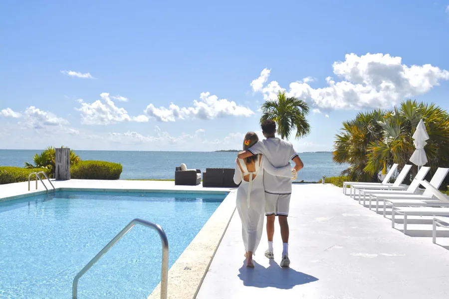 Casal de mãos dadas caminhando até a piscina